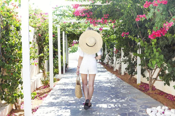 Pembe bougainvillea çiçeklerinin önünde hasır şapkalı sarışın kız. — Stok fotoğraf