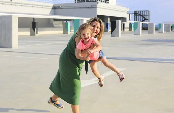 Mãe feliz com sua filhinha no fundo urbano — Fotografia de Stock