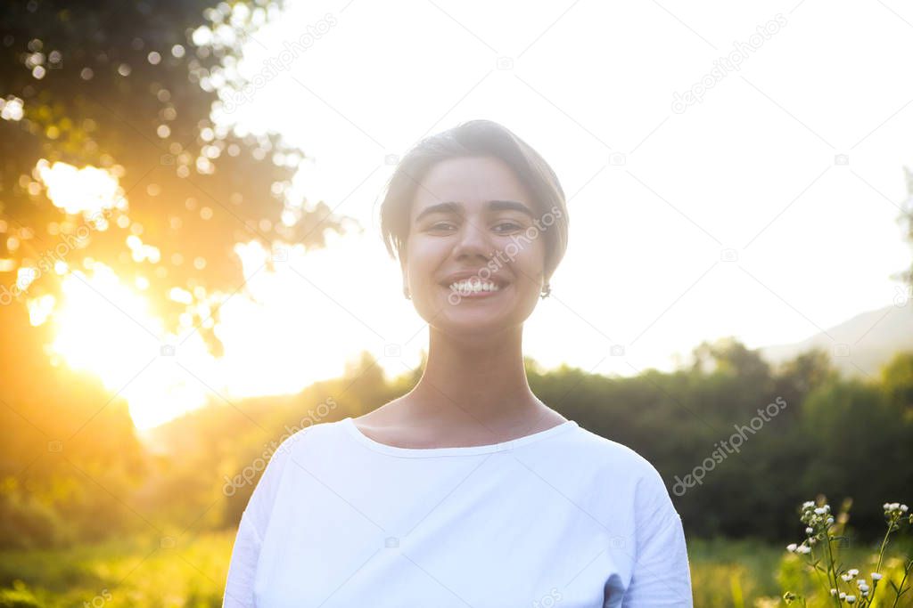 Portrait of cute brunette teen girl walking at meadow field