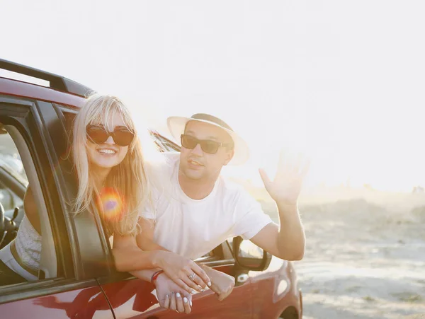 Młoda para stylowe w okulary przytulanie w pobliżu czerwony samochód — Zdjęcie stockowe