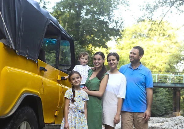 Feliz familia sonriente con niños en el coche con el río de montaña ba —  Fotos de Stock