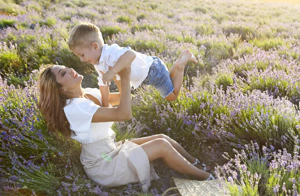 Gelukkig jong moeder en haar weinig in lavendel veld — Stockfoto