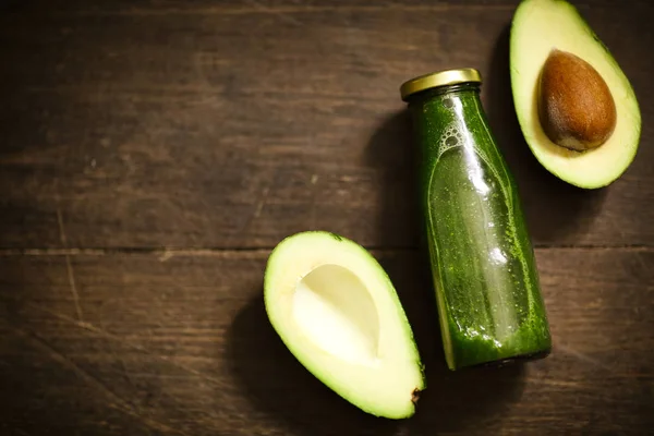 Smoothie con avocado verde in bottiglia di vetro su dorso in legno scuro — Foto Stock