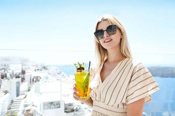 Donna che tiene un bicchiere di cocktail al frutto della passione a Santorini bac — Foto Stock