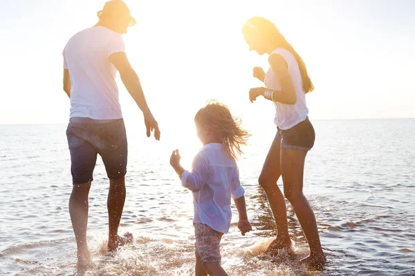 Familia feliz caminando en agua de mar —  Fotos de Stock