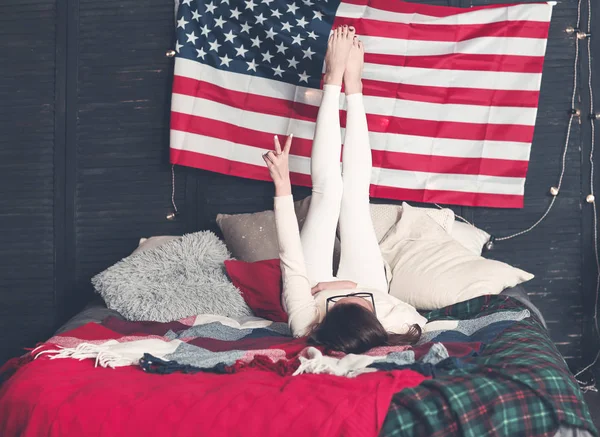 Красивая женщина в повседневной одежде на кровати с американским флагом на вале — стоковое фото
