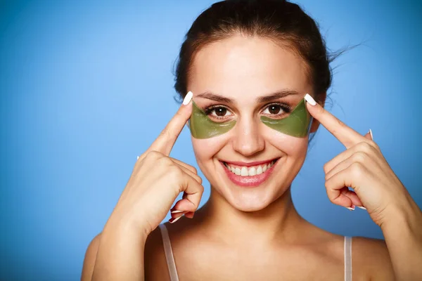 Menina bonita com manchas verdes sob os olhos em azul backg — Fotografia de Stock