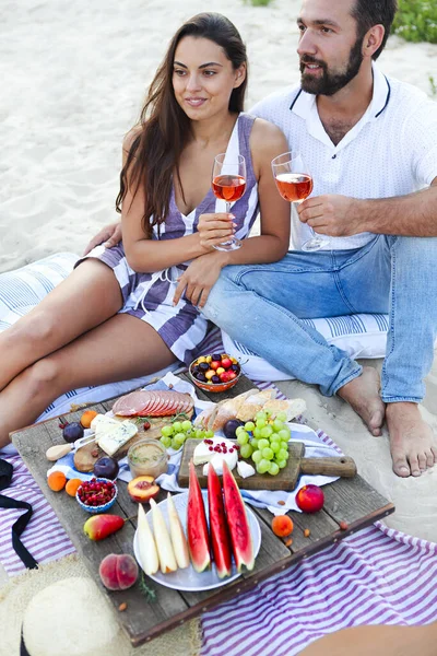 在海滩野餐时喝玫瑰酒的情侣 — 图库照片