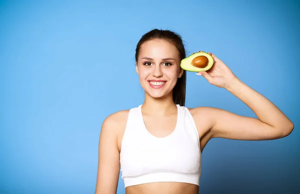 Tiro cortado de menina desportiva segurando abacate — Fotografia de Stock