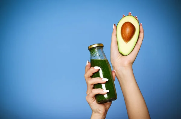 Close up de menina segurando abacate e smoothie verde — Fotografia de Stock