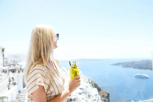 Donna che tiene un bicchiere di cocktail al frutto della passione a Santorini bac — Foto Stock