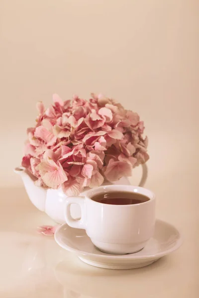 Porslin tekanna och kopp för te med massor av kronblad av rosa — Stockfoto