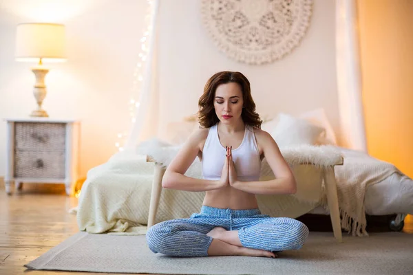 Lächelnde junge braunhaarige Frau im Pyjama praktiziert Yoga — Stockfoto