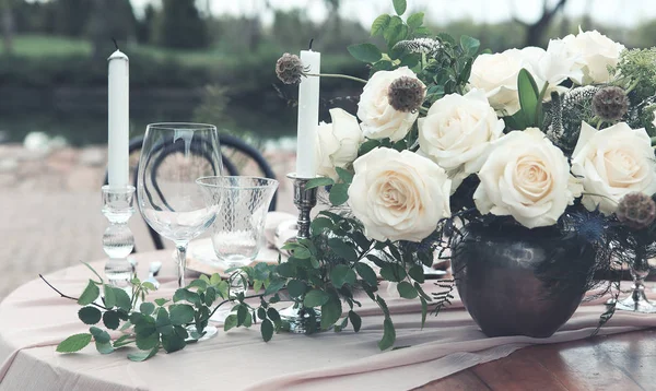 Velas y jarrón con rosas blancas colocadas en la mesa redonda cerca de ganar —  Fotos de Stock