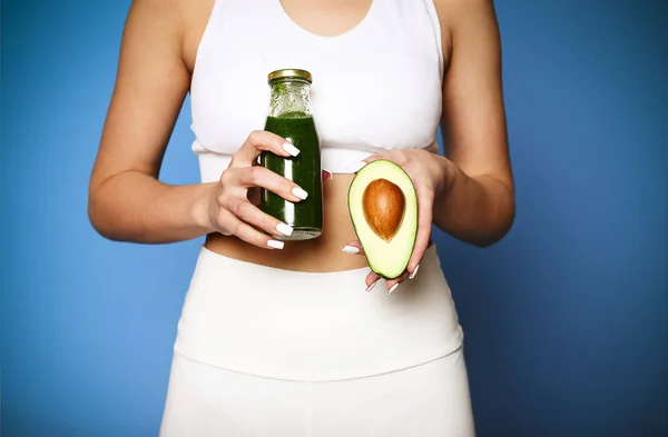 Närbild av ung flicka som håller avokado och grön smoothie — Stockfoto