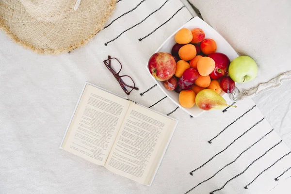 Πιάτο από ποικιλία φρούτων και βιβλίο στο κρεβάτι — Φωτογραφία Αρχείου