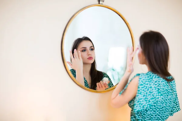 Mujer sonriente aplicando crema facial —  Fotos de Stock