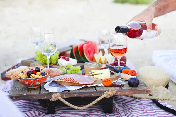 Mann schenkt Wein beim Picknick am Strand ein — Stockfoto