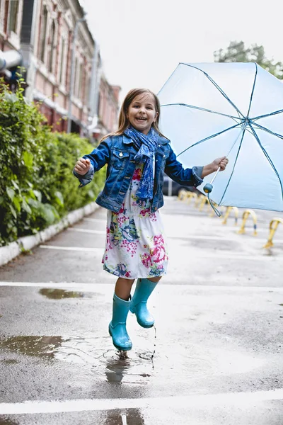 Glada liten flicka som har kul i pöl på gatan — Stockfoto