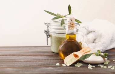 Salondaki kereste masasının üzerine yumuşak havlunun yanına konmuş zeytinyağından yapılmış çeşitli spa malzemeleri.