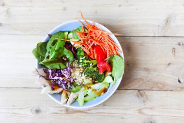 Üst kaseden taze sebzeler ve kereste masasına yerleştirilmiş tavuk parçaları.