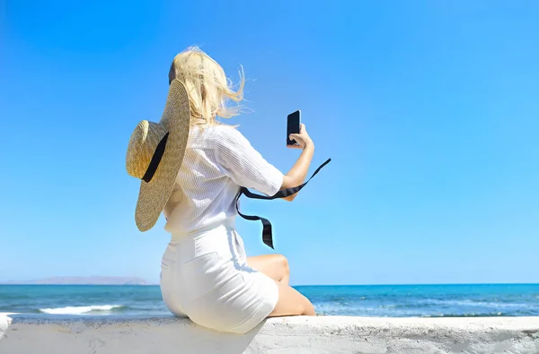 海と雲のない青空を背景に国境に座っている間 スタイリッシュな服を身に着けている匿名のスリム女性リゾートで晴れた日に — ストック写真