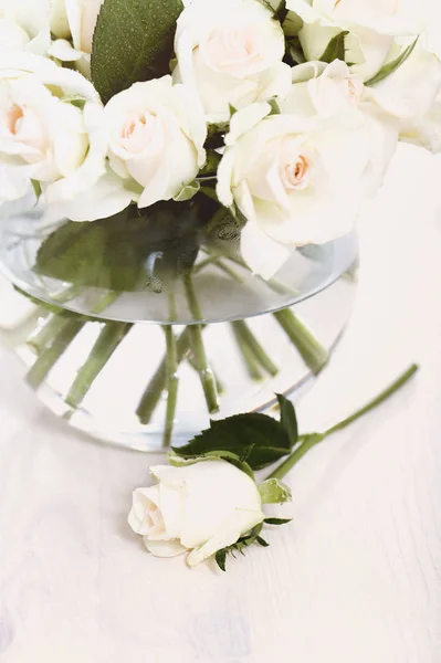 从上面的白色玫瑰组成的花束在玻璃花瓶与水 并放置在附近的白色木制背景 — 图库照片
