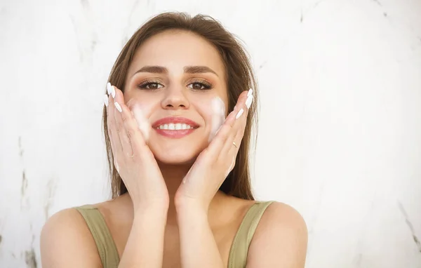 美しい若いブルネットの白人女性は泡で彼女の顔を洗う 化粧品のコンセプト — ストック写真