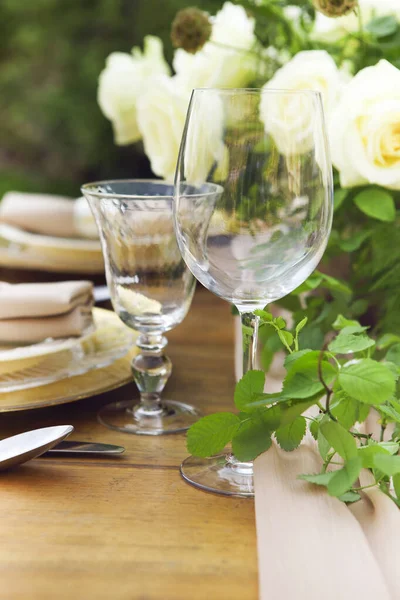 庭園のロマンチックなデート中にワイングラスの近くの丸いテーブルの上に白いバラとキャンドルや花瓶 — ストック写真