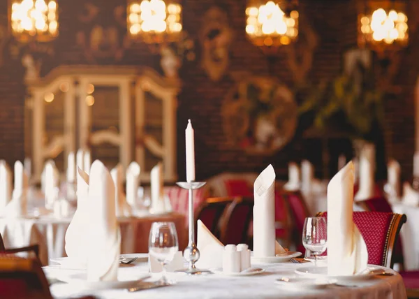 现代餐馆里 烛台上的白色蜡烛 时尚的玻璃杯和盘中折叠的餐巾 — 图库照片