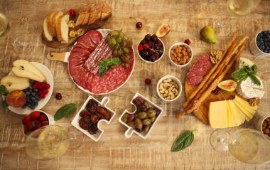 Beyaz şaraplı ahşap masa seti ve akşam oturma odasında çeşitli lezzetli peynir ve zeytinler.