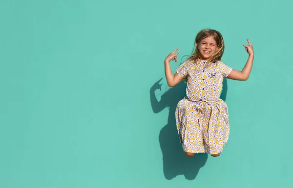 Niña Alegre Vestido Colorido Mostrando Gesto Cabra Saltando Contra Pared —  Fotos de Stock