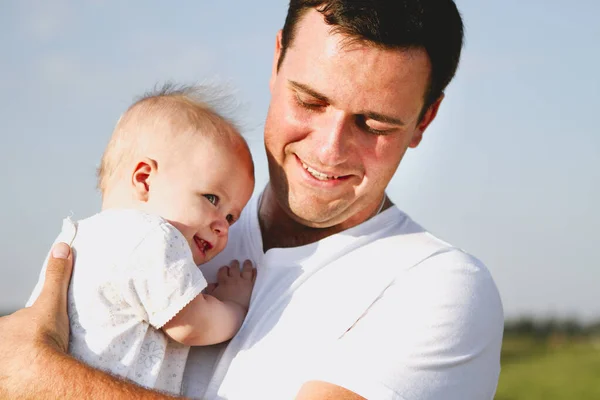 快乐的男人抱着可爱的女婴站在阳光灿烂的夏天的田野里 — 图库照片