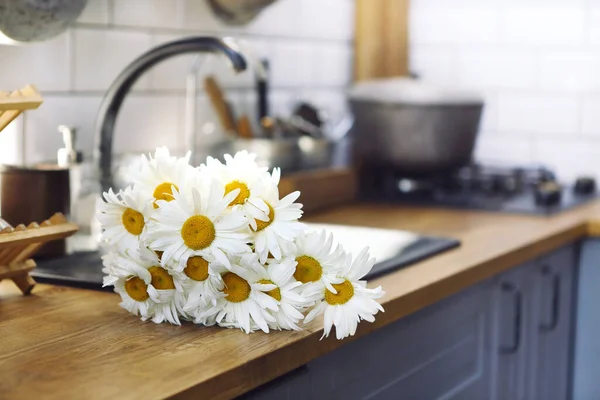 家のキッチンで木製のカウンターに置かれた美しい新鮮なデイジーの花の花束 — ストック写真