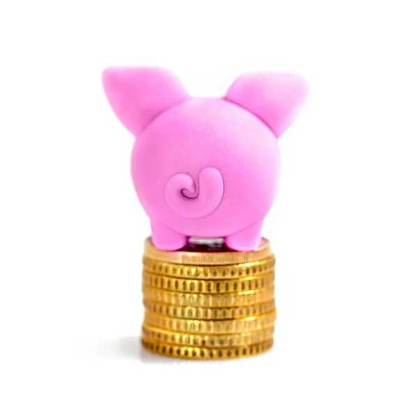 小さなピンクの貯金箱に置かれた光沢のあるコイン上に白い背景 — ストック写真