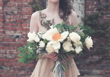 Şık pembe uzun elbiseler giyen ve elinde kurdeleli harika bir buket tutan ekili kadın.