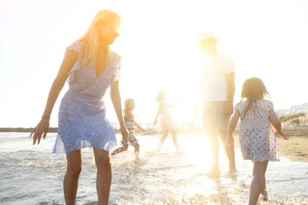 快乐的年轻父母 带着小女儿 在清澈的海水中散步 在夕阳西下的时候一起玩乐 — 图库照片