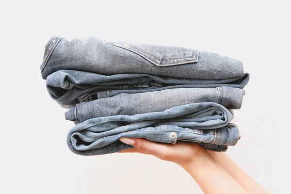 Jonge Winkelier Vrouw Met Een Stapel Jeans Een Lichte Achtergrond — Stockfoto