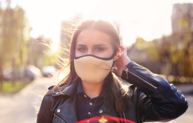 Gün batımında açık havada maske takan genç bir kadının portresi. Corona Virüsü, covid-19, salgın konsepti