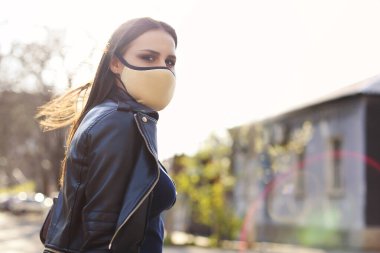 Gün batımında açık havada maske takan genç bir kadının portresi. Corona Virüsü, covid-19, salgın konsepti