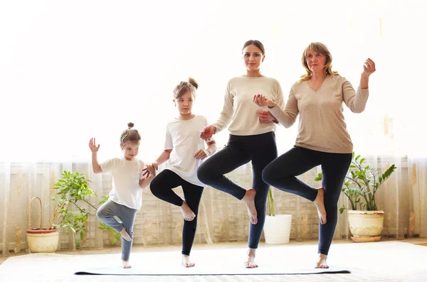 成年妇女和小女孩排成一排 在家里一起做瑜伽时伸出手来 — 图库照片