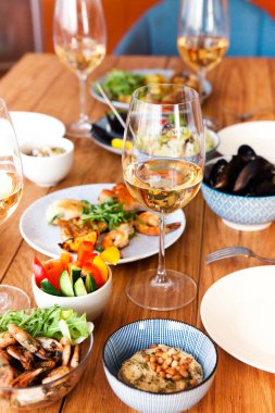 Yüksek açılı ahşap masa çeşitli ev yapımı tabaklar ve evde konforlu oturma odasında şarap ile servis edilir.