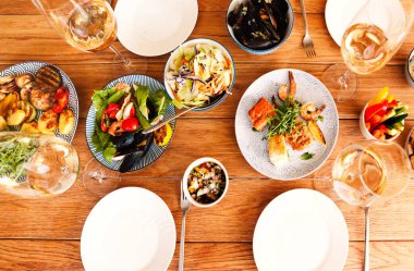 Yüksek açılı ahşap masa çeşitli ev yapımı tabaklar ve evde konforlu oturma odasında şarap ile servis edilir.