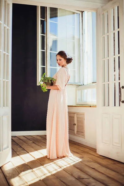 Belle femme portant une robe longue tenant plante maison . — Photo