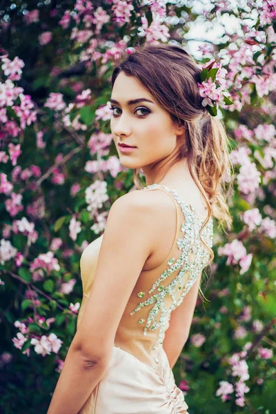 Retrato de una joven mujer hermosa posando en árboles de flores de primavera . —  Fotos de Stock