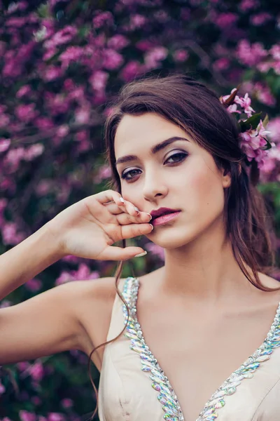 Retrato de una joven mujer hermosa posando entre los árboles de flores de primavera . —  Fotos de Stock