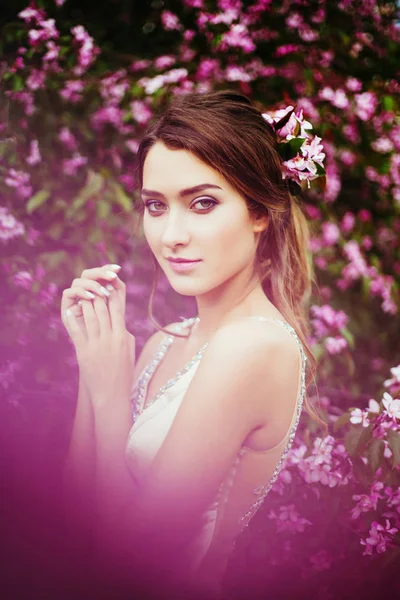 Портрет молодой красивой женщины, позирующей среди цветущих яблонь . — стоковое фото