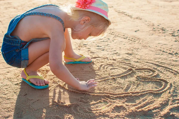 Söt liten flicka spelar med sand på stranden — Stockfoto