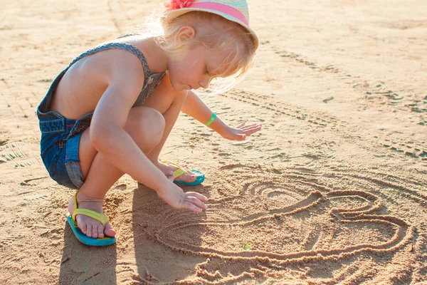 Söt liten flicka spelar med sand på stranden — Stockfoto