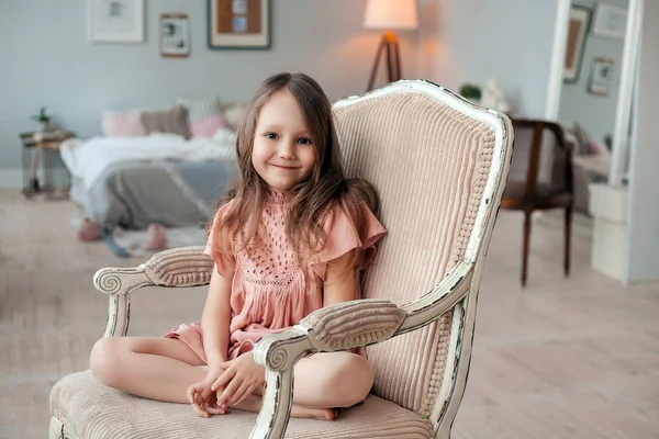 Portret van een schattig klein meisje, zittend in de stoel in haar kamer — Stockfoto